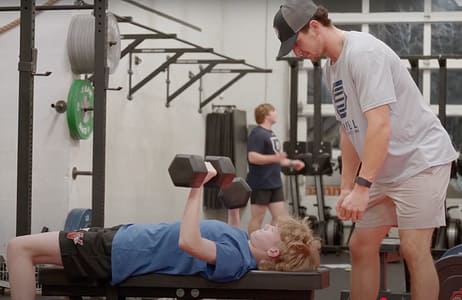 youth athlete bench pressing with coach