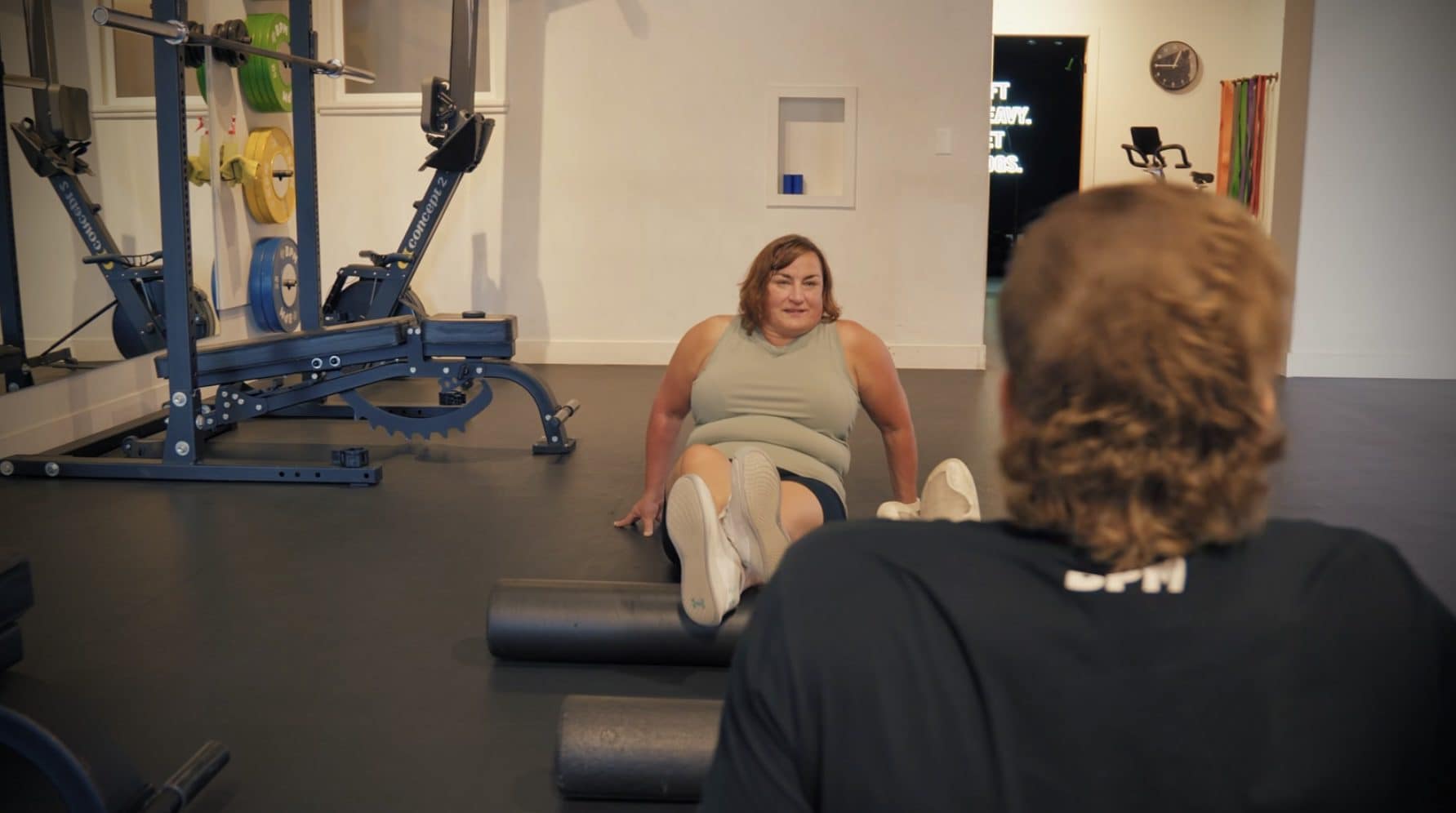 A female personal training client foam rolling her calves with her personal trainer at BPM Fitness Centre in Victoria, BC
