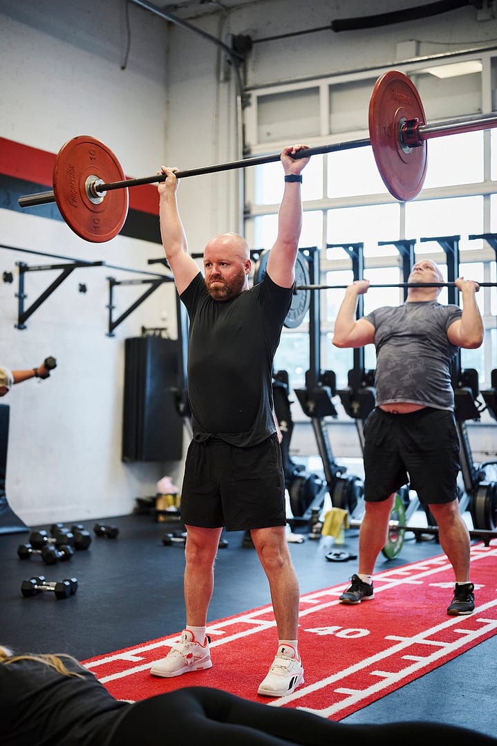 a man pushing a barbell overhead in a fitness class at BPM Fitness Centre